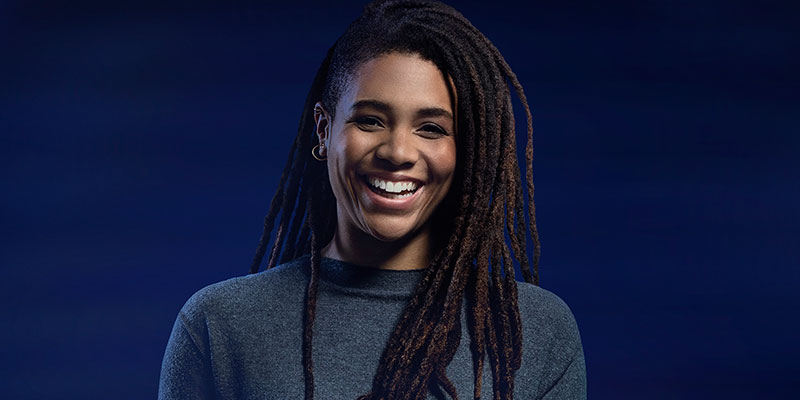 A woman with dreadlocks smiles very broadly
