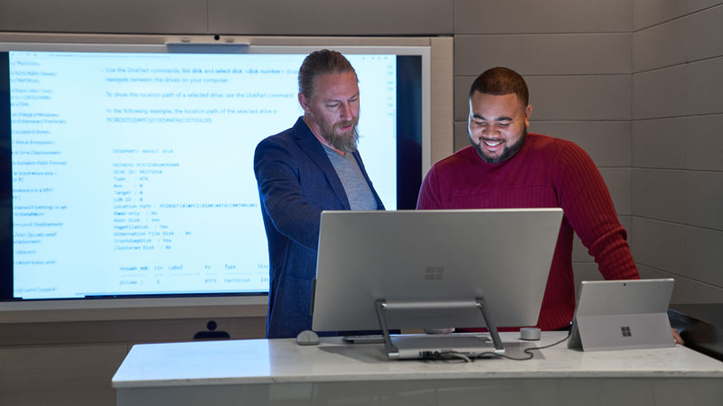 Two people looking at a Surface Studio