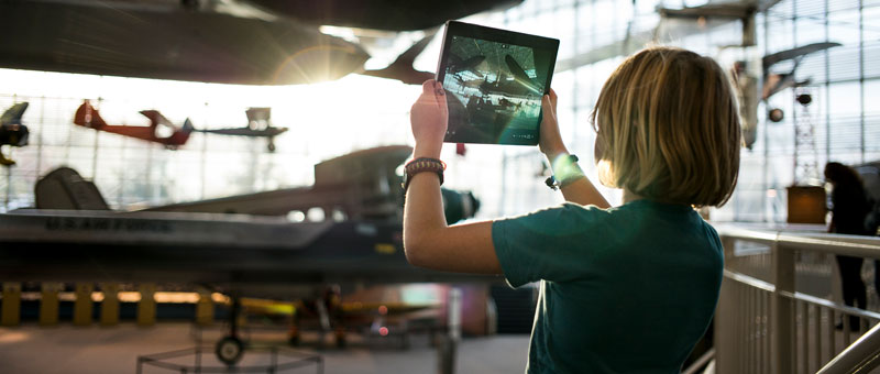 person in an airline hangar looking at a tablet device