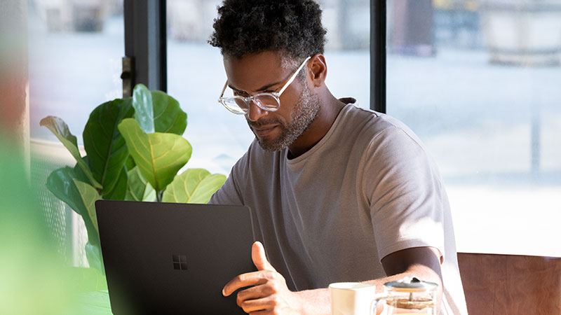 A man in an office looks intently at his Microsoft Surface Laptop screen